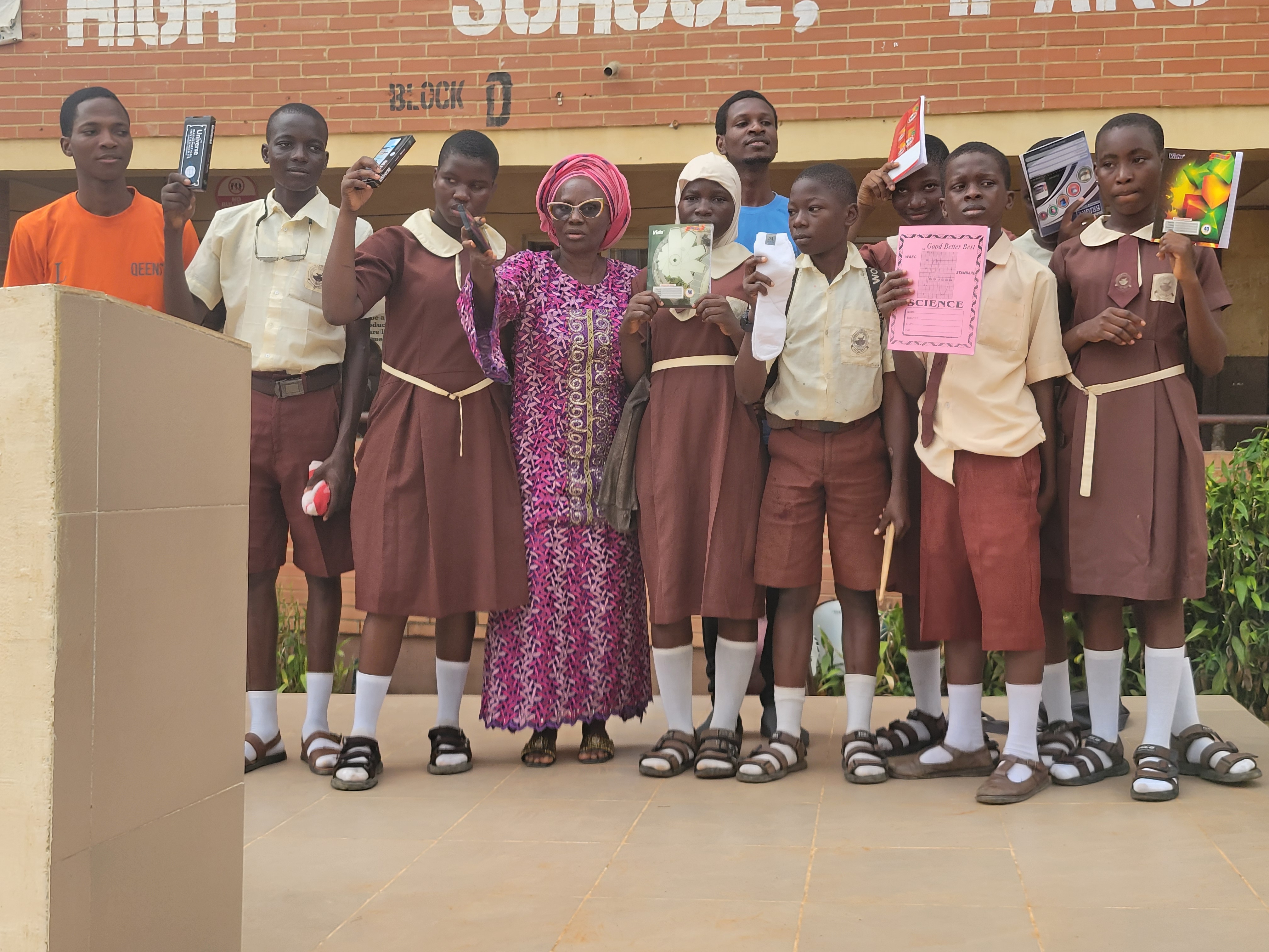 Students and school staff presenting donated science kits and textbooks.